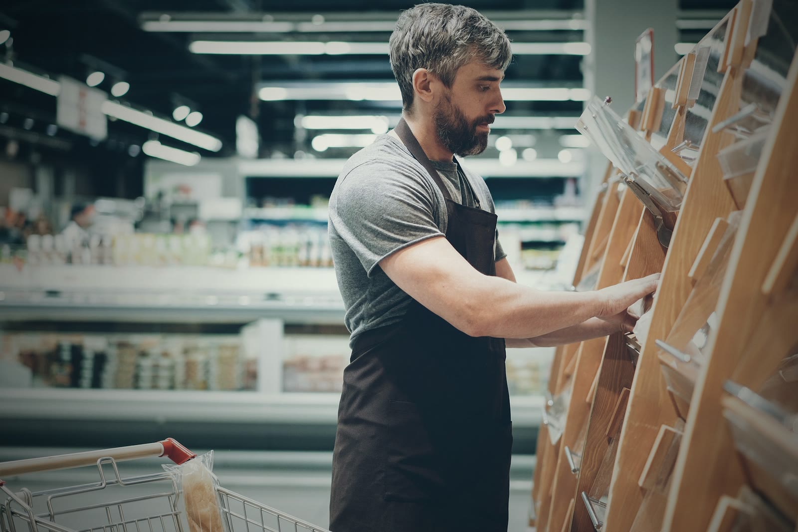 A store worker restocking packaged bread on a grocery shelf